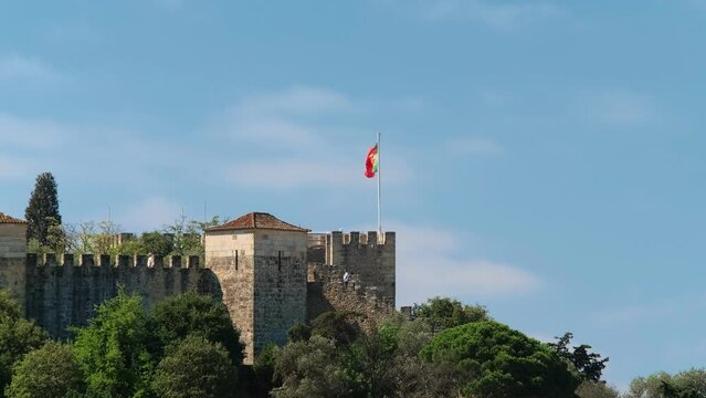 Saint George Castle Castelo de Sao Jorge in Lisboa, Portugal with walking tourists and large Portuguese flag