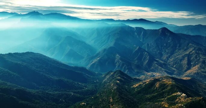 Blue haze covering the tops of mountains. Beautiful rocky landscape in the fog from aerial view.