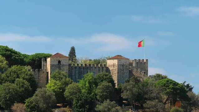 Saint George Castle Castelo de Sao Jorge in Lisboa, Portugal with walking tourists and large Portuguese flag