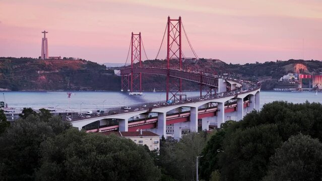 View of Lisbon from Miradouro do Bairro do Alvito tourist viewpoint with Tagus river, traffic on 25th of April Bridge, and Christ the King statue at sunset. Lisbon, Portugal, Europe