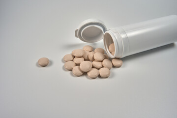 Pills spilled from a container on a white backgroun