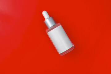 Moisturizing facial essence on a red background. Serum in the waves. Anti-aging cosmetics. Mockup.