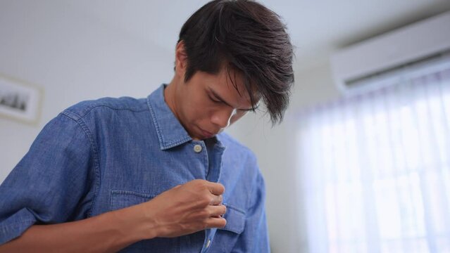 Asian young amputee without arm wearing a t-shirt while sitting on bed. 