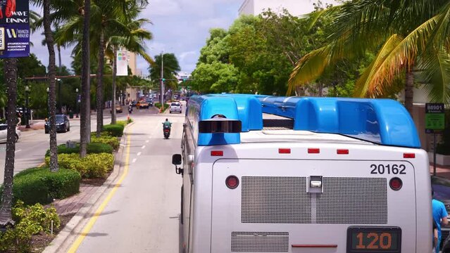 Miami bus driving in Miami South Beach street. Tropical beach vacation travel in USA. American urban life and tourism destination.