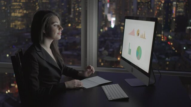Young Confident Woman Working in Modern Office on Computer Desk At Night
