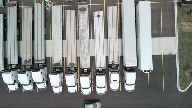 Parking of logistics warehouse with semi trucks and cargo trailers, aerial above view.