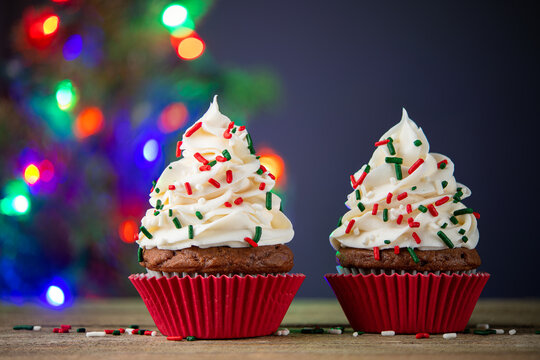 Cupcake. Cupcakes and Christmas Tree. Red cup liners. Merry Christmas. Tasty baking cupcakes, cake or muffin with white cream icing, frosting and colored sprinkles. Homemade bakery, confectionery shop