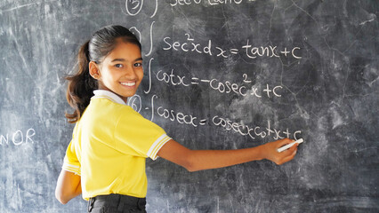 Happy Rural School Girl wearing School Uniform Standing in Front of A Black Board.