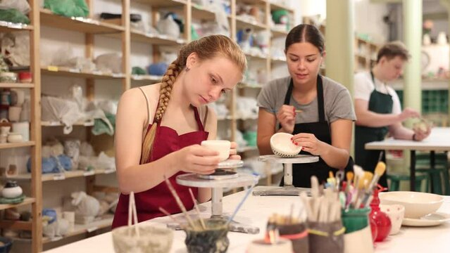 Teenage girl makes ceramic cup in ceramic workshop. High quality 4k footage