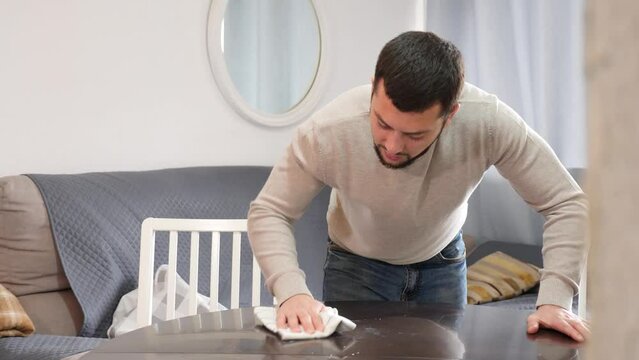 Adult Man cleans the table with a rag at home. High quality 4k footage