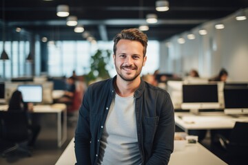 Fototapeta premium Smiling portrait of a happy young caucasian man working for a modern startup company in a business office