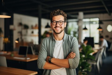 Obraz premium Smiling portrait of a happy young caucasian man working for a modern startup company in a business office
