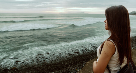 Beautiful young Latina girl, by the sea enjoying the marine breeze. Space for text.