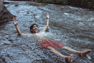 Carefree young Asian man floating in river with happy expression. 