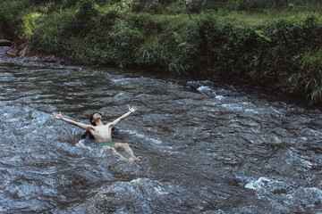 Young man feel free enjoying a river flow at countryside. 