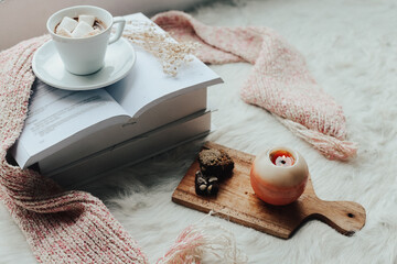 Winter mood, hot drink on stack of books with knitted decoration