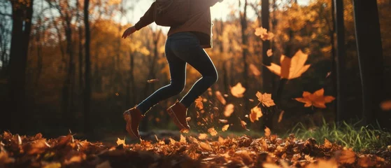 Foto op Plexiglas Person playfully jumping into a pile of leaves, their hands and legs creating a sense of action. The blurred foliage adds a touch of magic to the scene, capturing the essence of a carefree autumn day © Daunhijauxx