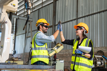 Team of Engineers is controlling robot arm machine welding steel, worker using forcing welding with a control screen which is used for precision welding control.