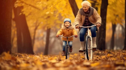 Fotobehang shot of a kid teaching an elderly person to ride a bicycle in autumn © Daunhijauxx