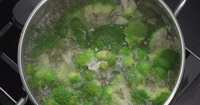 Boiling broccoli in a pot on induction stove. Slow motion