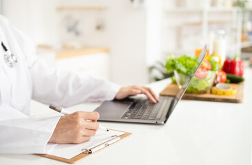 Female nutritionist doctor writing vegetable diet plan