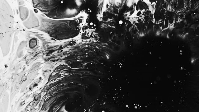 Black ink. Fluid explosion. Dark liquid drops stain blotch spreading on light abstract background with free space.
