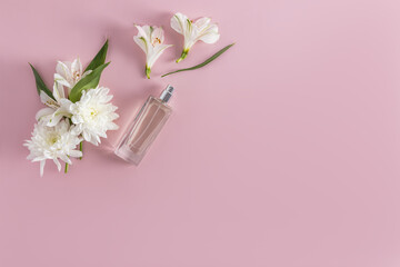 Beautiful composition of a bottle with cosmetics, spray or perfume and white flowers on a pink background. Top view. Flat lay. A copy space.
