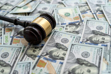 Gavel above piles of new 100 dollars bills as finance background.  Justice concept