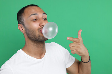 Man blowing bubble gum on green background. Space for text