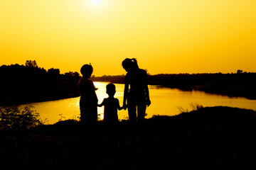 Silhouette of a family comprising a father, mother and two children happy family the sunset.Concept of friendly  - 646230323