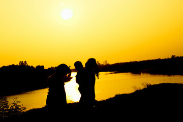 Silhouette of a family comprising a father, mother and two children happy family the sunset.Concept of friendly  - 646230344