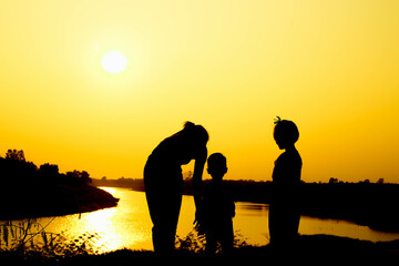 Silhouette of a family comprising a father, mother and two children happy family the sunset.Concept of friendly  - 646230359