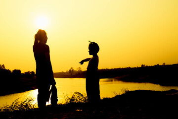 Silhouette of a family comprising a father, mother and two children happy family the sunset.Concept of friendly 