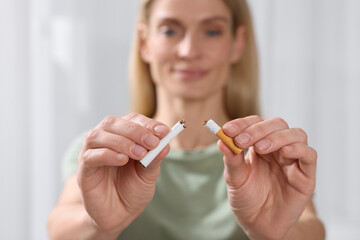 Woman with broken cigarette on light background, selective focus. Quitting smoking concept