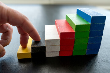 close up of businessman hand climbing upstairs on color wooden block,