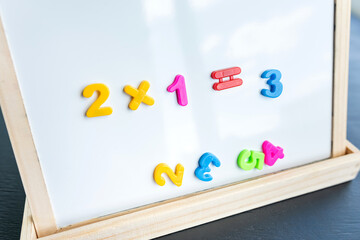 White board with magnetic numbers, primary school math. Solving examples