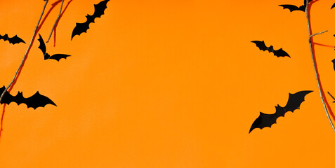 Halloween and decoration concept. Black bats flying over tree, orange background. Horror concept. Banner. Halloween with copy space for text. Greeting card.