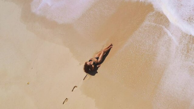Aerial drone views a beautiful tropical beach with white sand palm trees and clear water and a woman model in a black bikini. Travel and resort leisure conceptual footage with copy space