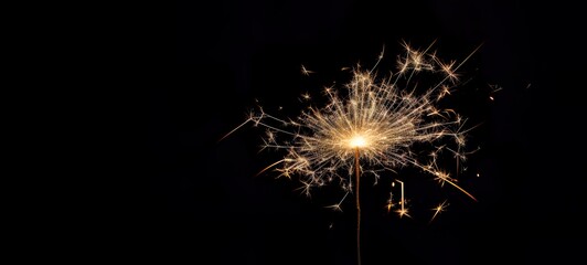 A magic explosion of sparks on a dark background. Sparkler glowing, burning, light. Celebrate a small firework in the night for fairy birthday, New Year and party.