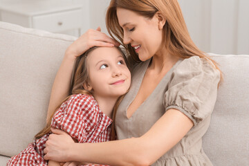 Mother and her cute daughter on sofa at home