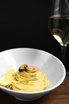Tasty capellini with mussels and lemon on wooden table, closeup. Exquisite presentation of pasta dish