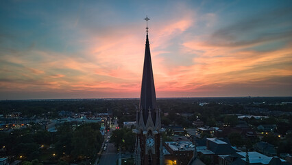 Fototapeta premium The silhouette of the cross and church bell tower in sunrise, sunset time. Aerial shot