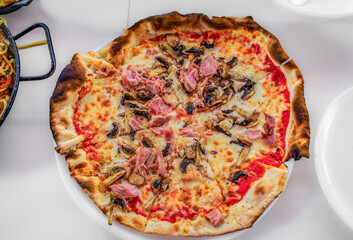 Neapolitan pizza with tomato sauce, cheese, ham and mushrooms at an Italian restaurant in the Old Town, Vieille Ville of Nice, South of France