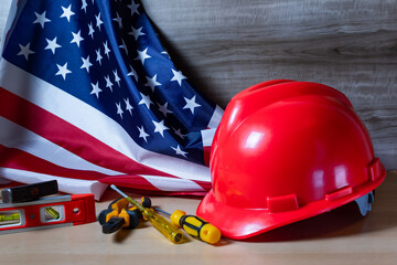Red helmet and tools on large American flag, Labor day background.