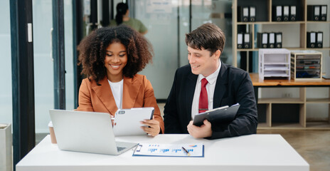 Businesswomen work and discuss their business plans. A Human employee explains and shows her colleague the results paper in modern office.