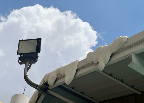 a photography of a street light on a roof covered in snow, solar collector on roof with snow on top of it.