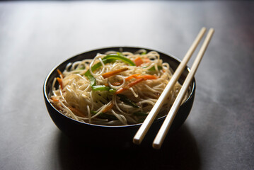 Wok tossed udon noodles served in a bowl. Close up, selective focus.