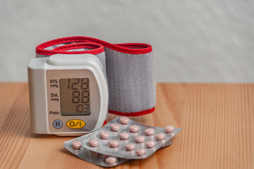 Small modern blood pressure measuring device and tablets are set at the table with copy space...