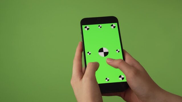 woman typing on phone in front of green screen