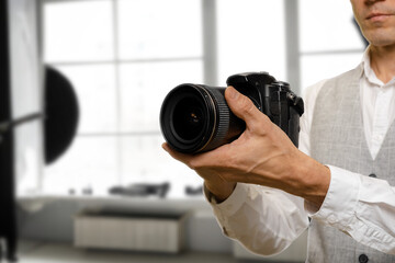 Male photographer with professional equipment ready in studio, The focus of the image is a close-up of the photographer's hands, showcasing the intricate connection between the artist and their tools